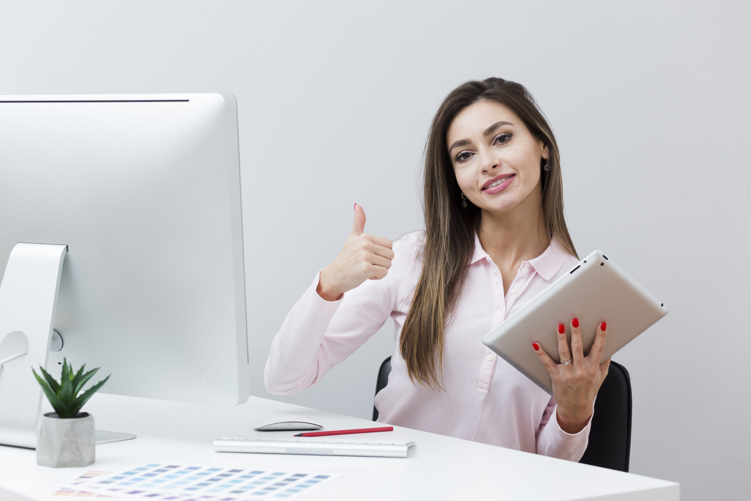 icon-medias-woman desk giving thumbs up while holding tablet scaled